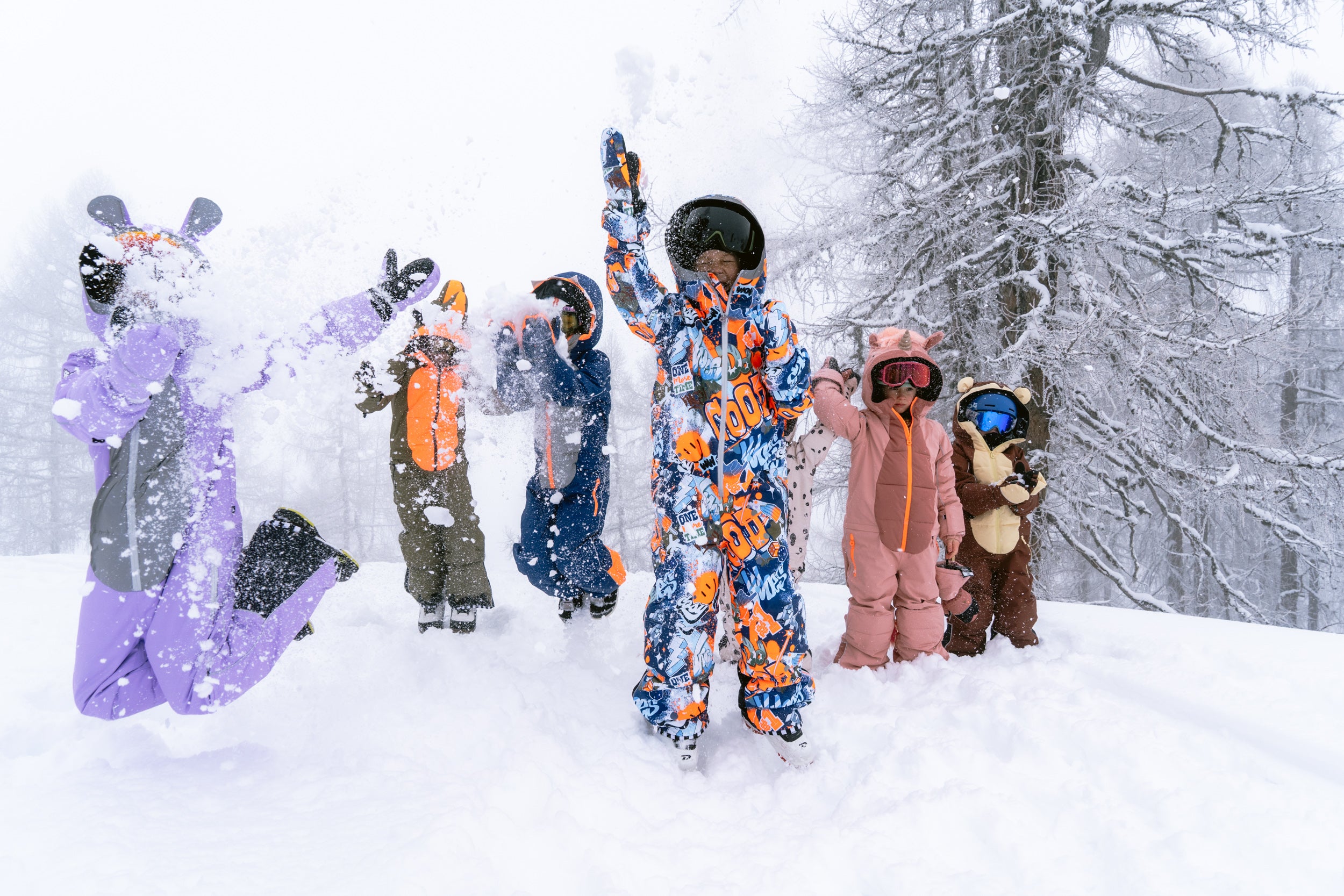 Six children in WeeDo snowsuits skiing and snowboarding in fresh snow.