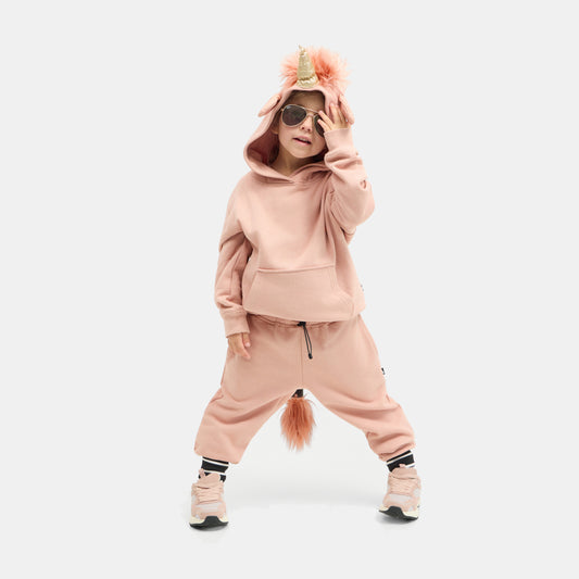 Child standing in the dusty pink UNIDO Sweatsuit, hood up with the glitter unicorn horn and faux-fur mane.